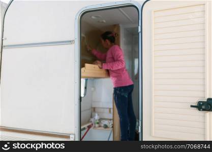 Young blonde woman painting and restoring caravan
