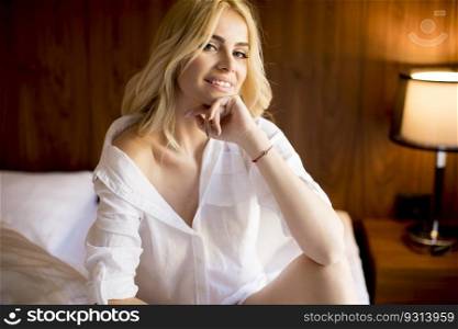 Young blonde woman sitting on the bed in the room