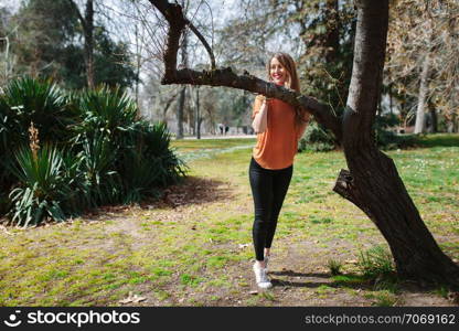 Young blonde woman supported on a tree with black jeans