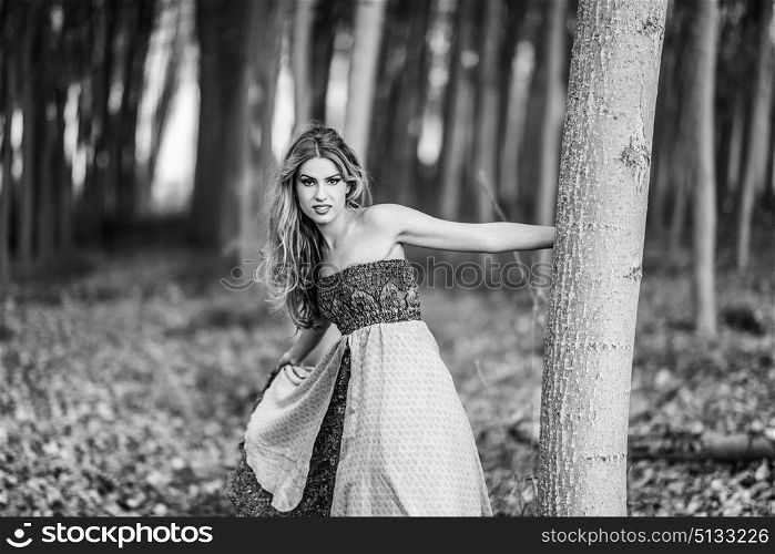 Young blonde woman wearing vintage dress in a poplar forest