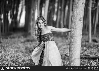 Young blonde woman wearing vintage dress in a poplar forest