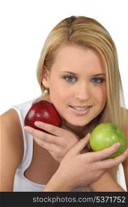 Young blonde woman with a red and a green apple