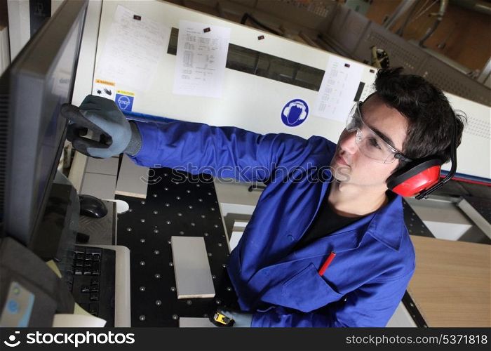 young blue collar in factory with computer