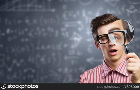 Young botanist. Young man in casual looking in magnifier