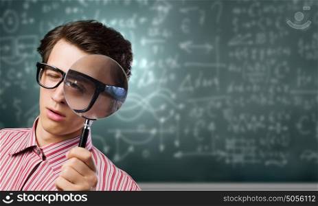 Young botanist. Young man in casual looking in magnifier