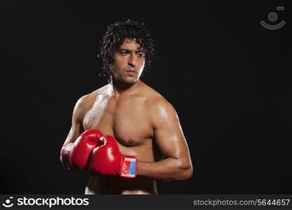 Young boxer looking away over black background