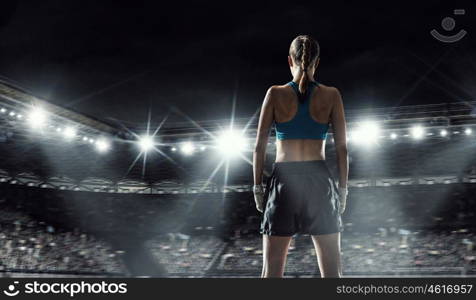 Young boxer woman at ring. Young pretty boxer woman standing in lights of sport arena