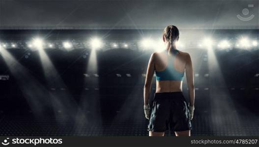 Young boxer woman at ring. Young pretty boxer woman standing in lights of sport arena