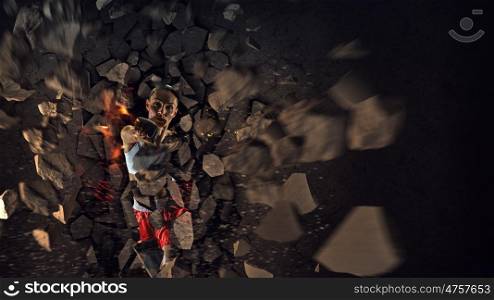 Young boxer woman. Young boxer woman breaking concrete wall with kick