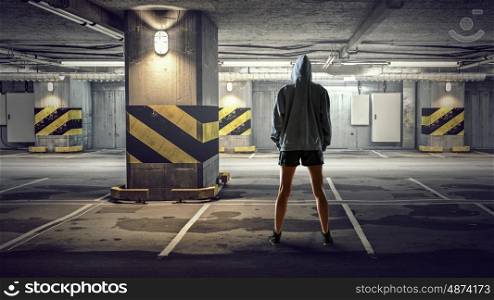 Young boxer woman. Young boxer woman standing with back in underground parking. Mixed media
