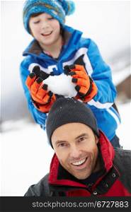 Young Boy About To Drop Snowball On Fathers Head