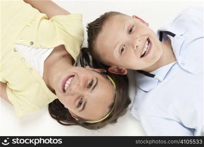 young boy and girl lying head to head looking up at camera