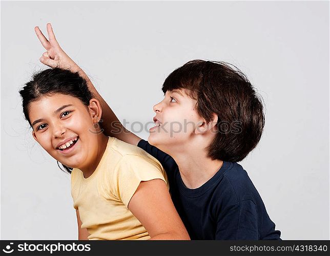 Young boy and girl playing, young boy holding up fingers as rabbit ears