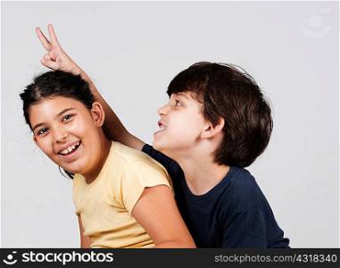 Young boy and girl playing, young boy holding up fingers as rabbit ears