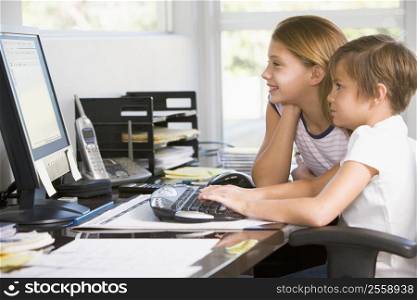 Young boy and young girl in home office with computer smiling