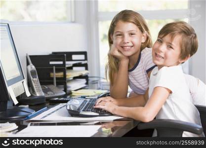 Young boy and young girl in home office with computer smiling