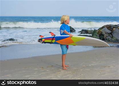 Young boy at beach, holding surfboard