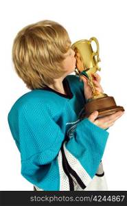 Young boy athlete kissing the championship trophy. Face is visible in the reflection on the cup.