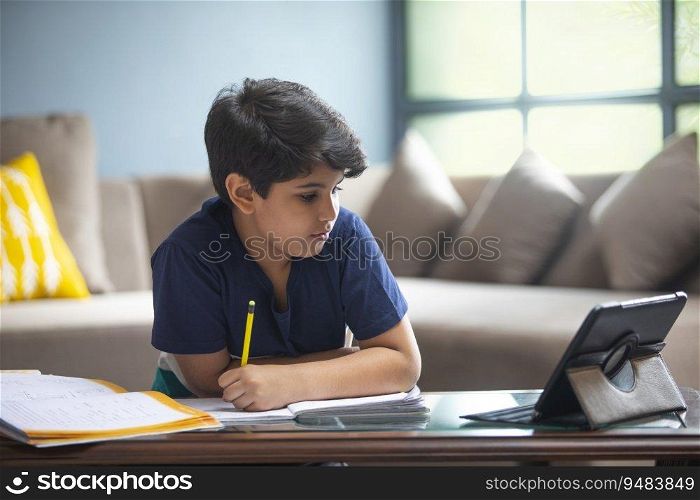 YOUNG BOY ATTENDING HIS CLASS ONLINE ON HIS TABLET