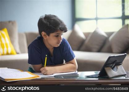 YOUNG BOY ATTENDING HIS CLASS ONLINE ON HIS TABLET