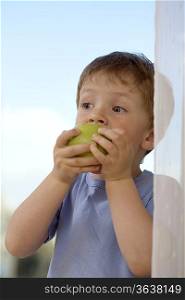 Young boy biting into an apple
