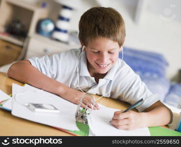 Young Boy Doing His Homework While Listening To Music On His MP3 Player