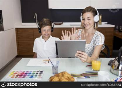 young boy doing video conference together with mother