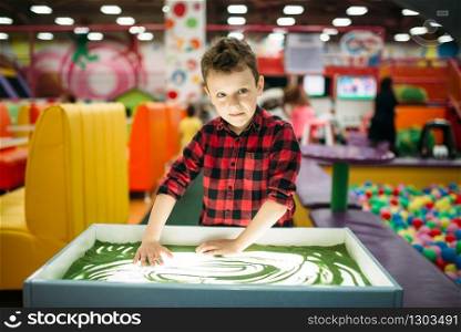 Young boy draws in the sand, attraction in entertainment center. Happy childhood. Adventure time