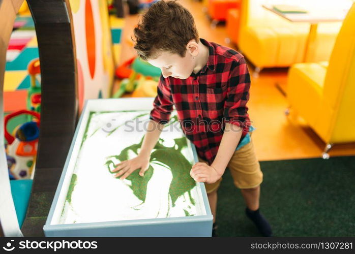 Young boy draws in the sand, attraction in entertainment center. Happy childhood. Adventure time. Young boy draws in the sand, entertainment center