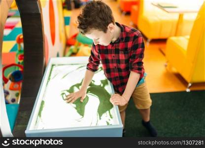 Young boy draws in the sand, attraction in entertainment center. Happy childhood. Adventure time. Young boy draws in the sand, entertainment center