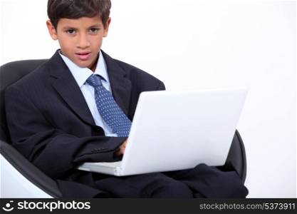 Young boy dressed in an adult business suit with a laptop