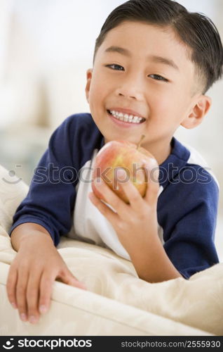 Young boy eating apple in living room smiling