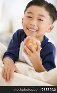 Young boy eating apple in living room smiling
