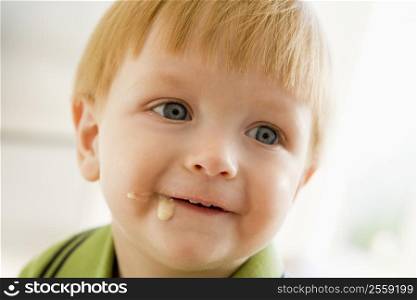 Young boy eating baby food with mess on face