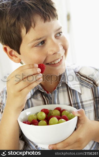 Young Boy Eating Bowl Of Fresh Fruit