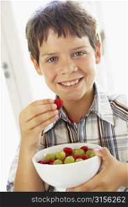 Young Boy Eating Bowl Of Fresh Fruit