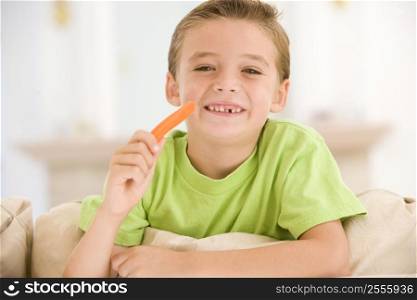 Young boy eating carrot stick in living room smiling