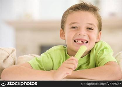 Young boy eating celery in living room smiling