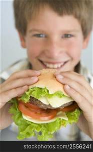 Young boy eating cheeseburger smiling