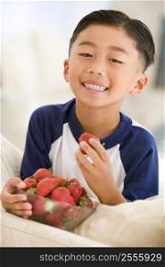 Young boy eating strawberries in living room smiling