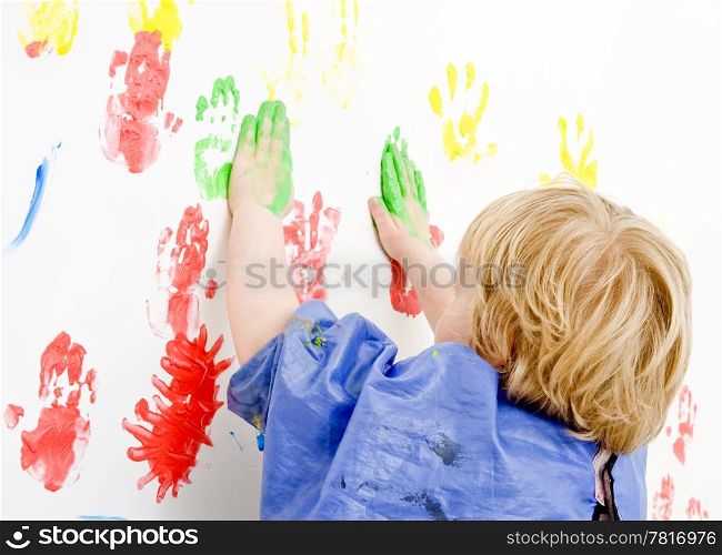 Young boy finger painting on a wall