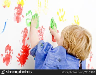 Young boy finger painting on a wall