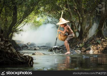 Young boy fisherman on river stream / fish in harpoon