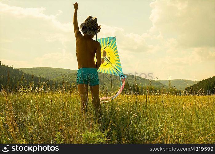 Young boy flying kite in field, rear view