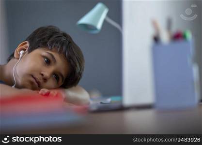 Young boy getting bored while attending online class on laptop 