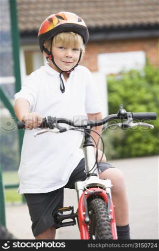 Young boy getting on bicycle outside school