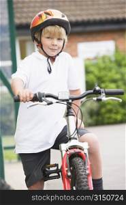 Young boy getting on bicycle outside school