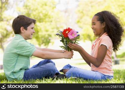 Young boy giving young girl flowers and smiling