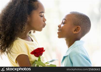 Young boy giving young girl rose and smiling