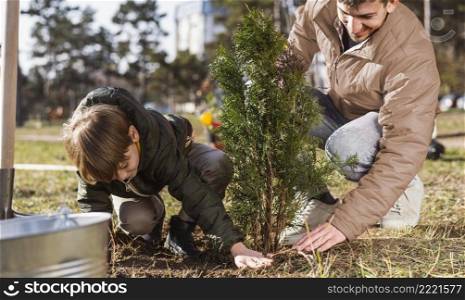 young boy his father planting tree outdoors